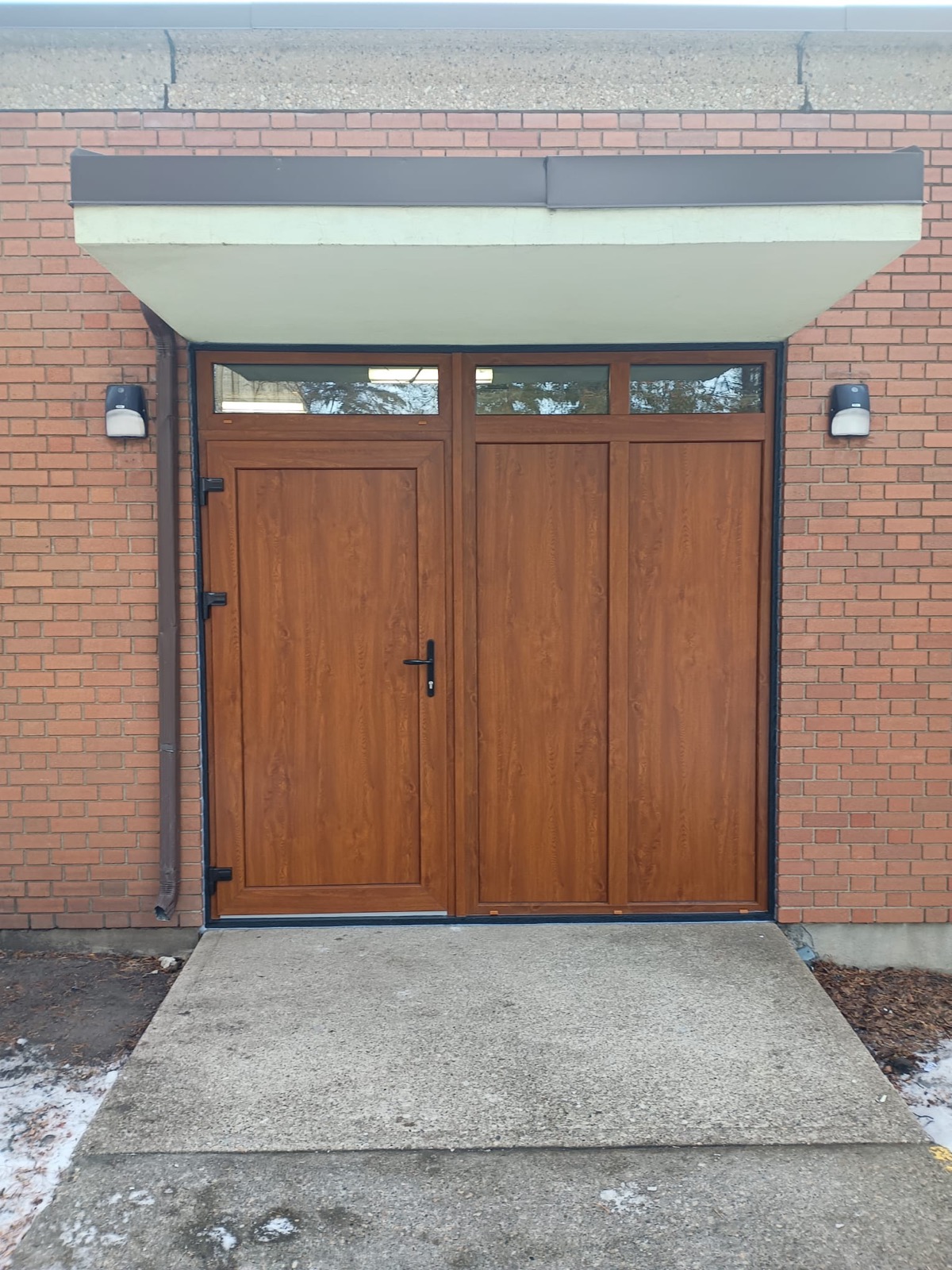 Double wood-grain entry doors with transoms set in brick commercial facade