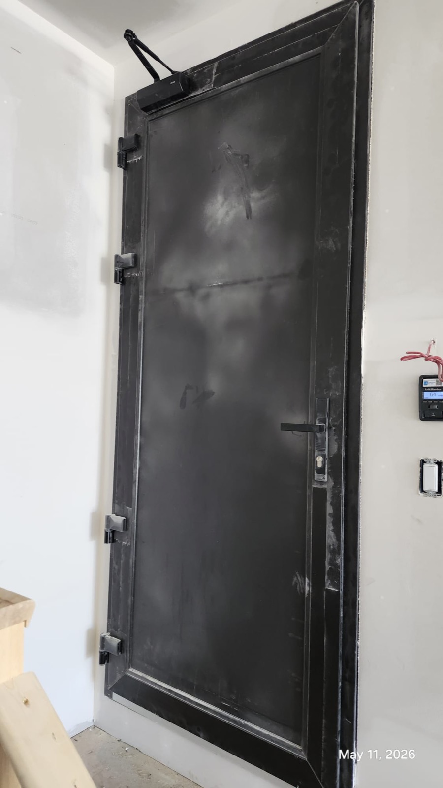 Heavy black steel security door in commercial mechanical room context