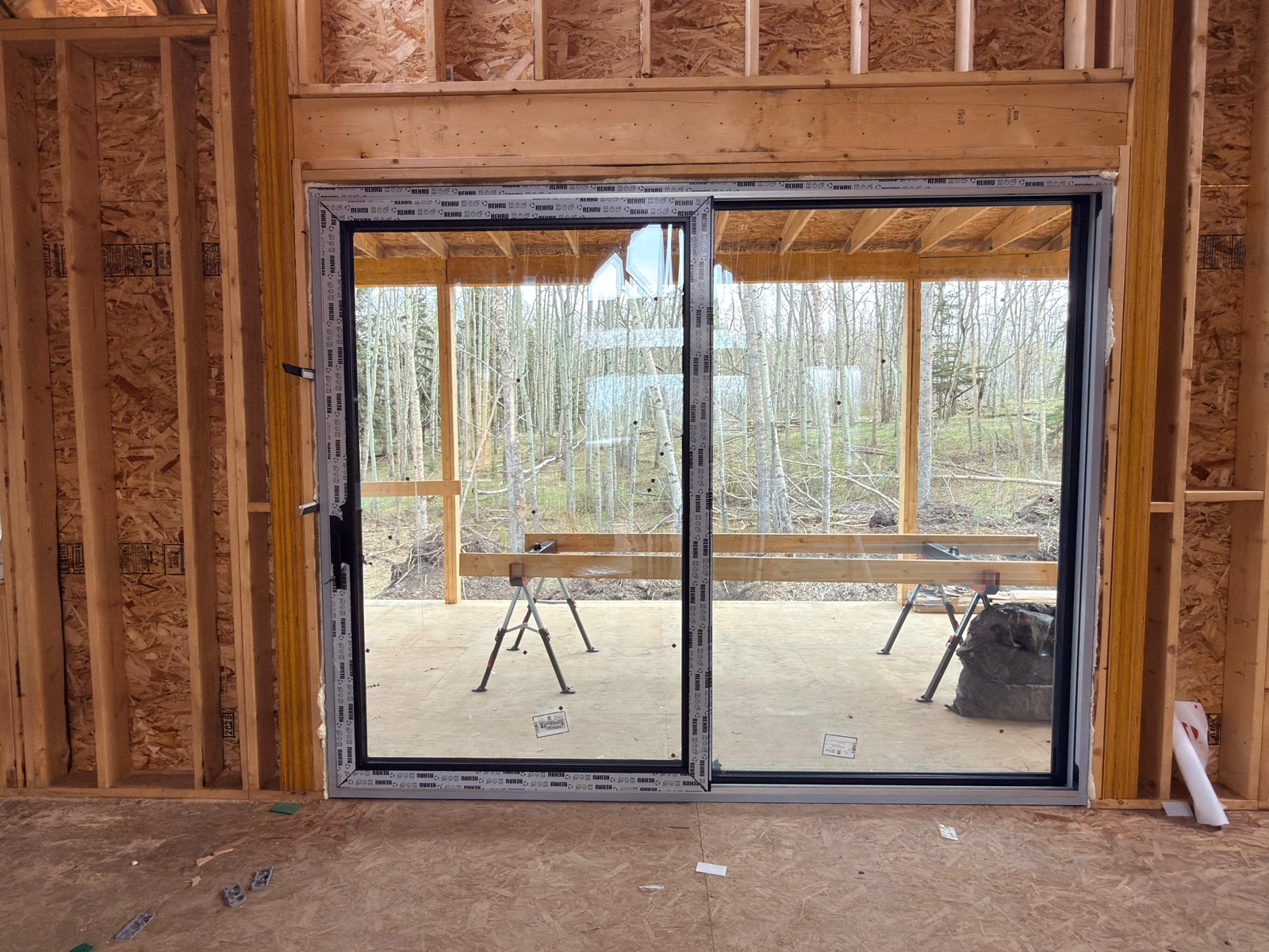 Wide black-frame sliding patio door unit in raw rough opening