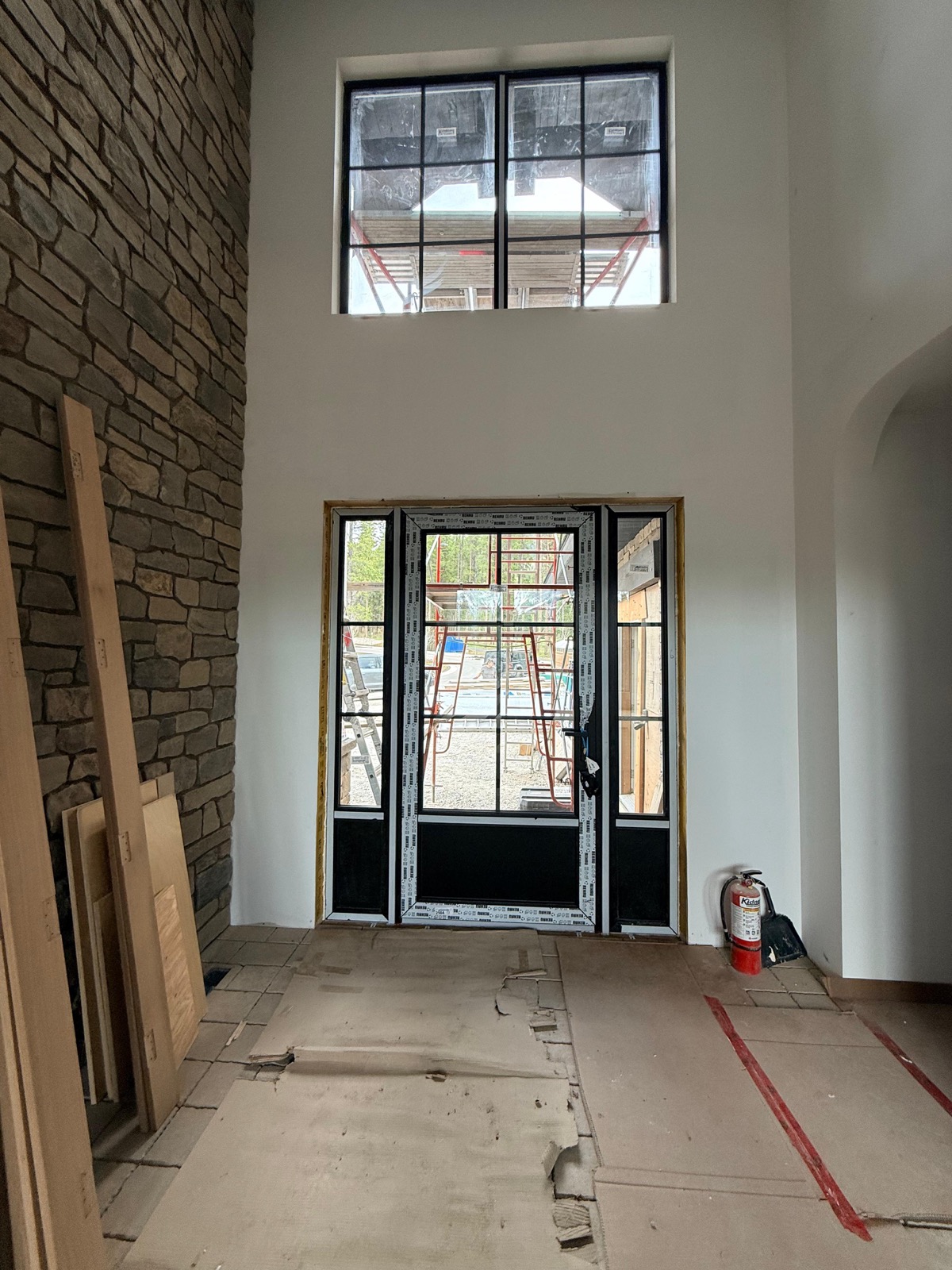 Double-height foyer with transom and entry door plus sidelites against stone wall